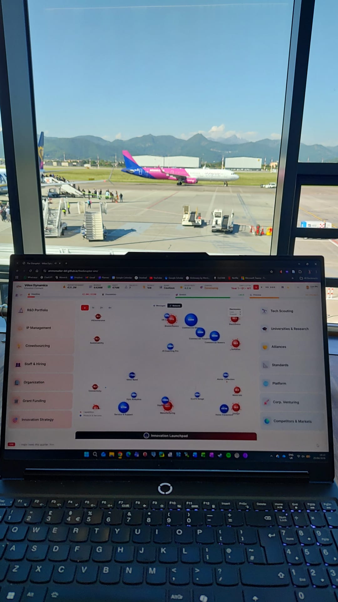 The Disruptor played on a laptop at Genova airport, with a Wizz Air aircraft and mountains visible through the window